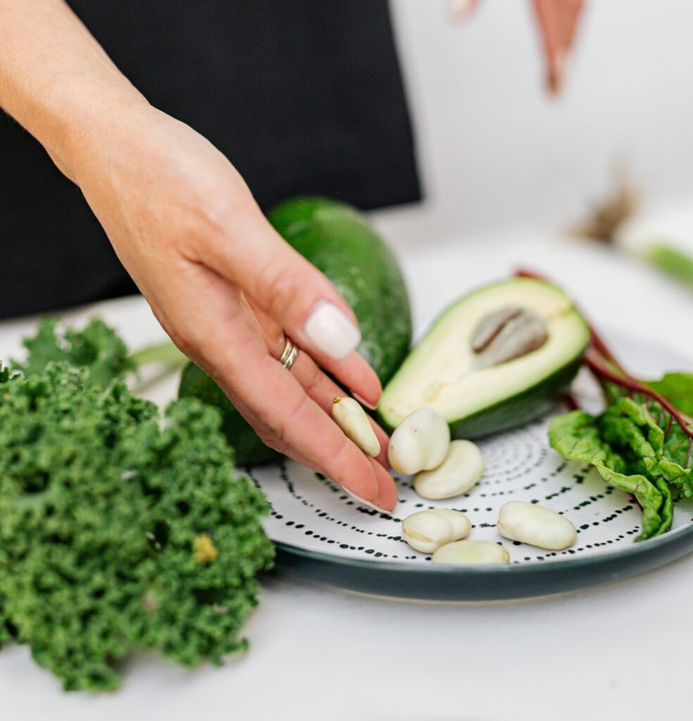 Hands slicing avocado on a cutting board beside beans and fresh ingredients